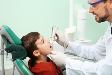 Photo of Professional dentist working with little patient in modern clinic