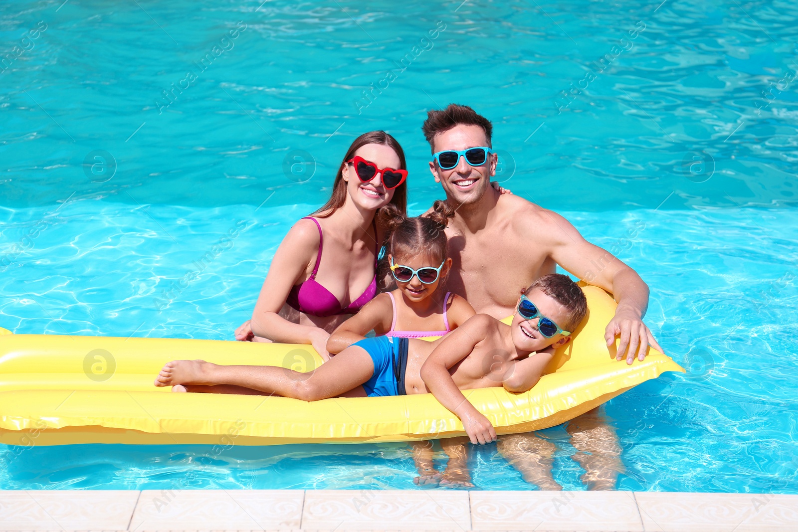 Photo of Happy family with inflatable mattress in swimming pool