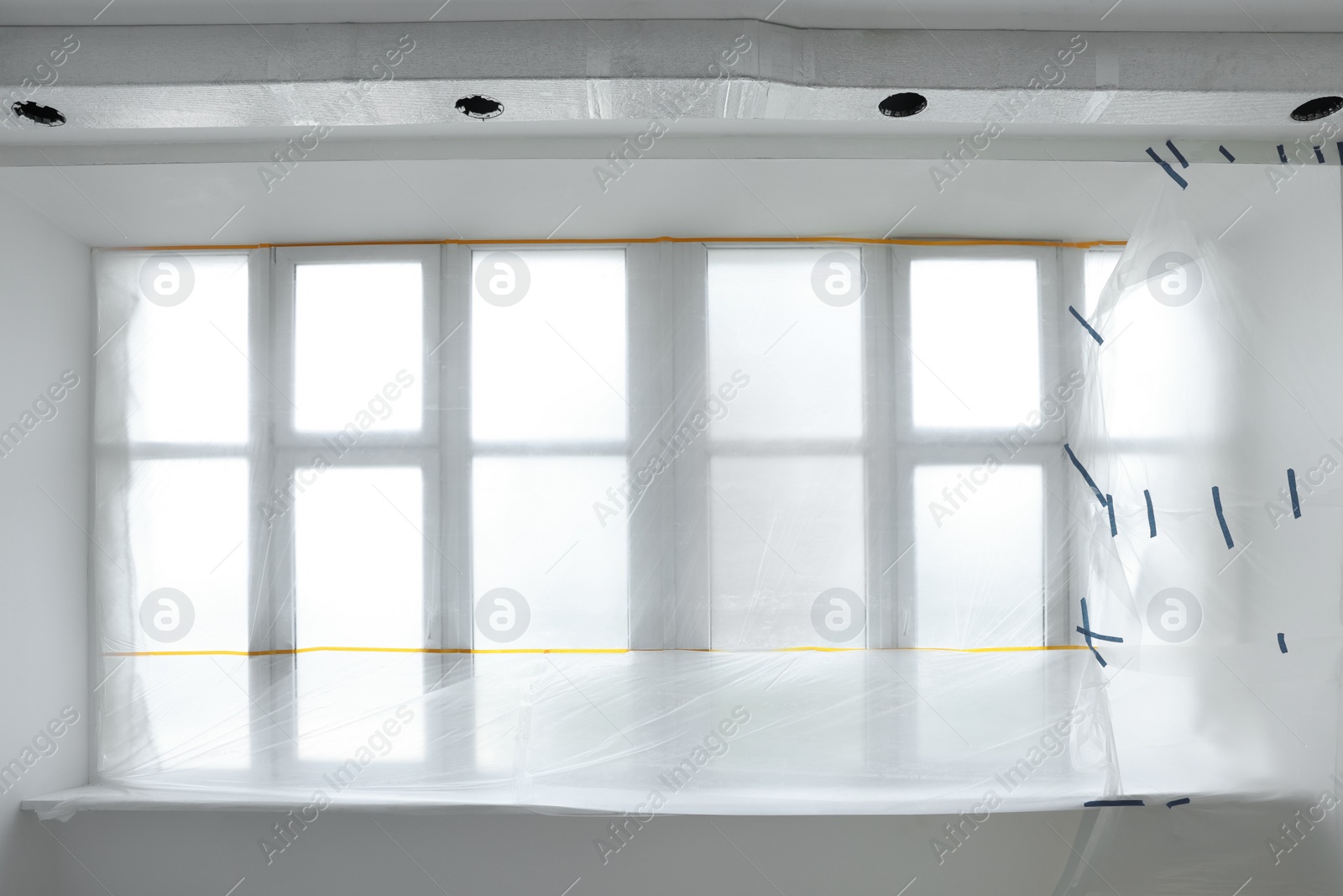 Photo of Window covered with plastic film and insulation tape indoors