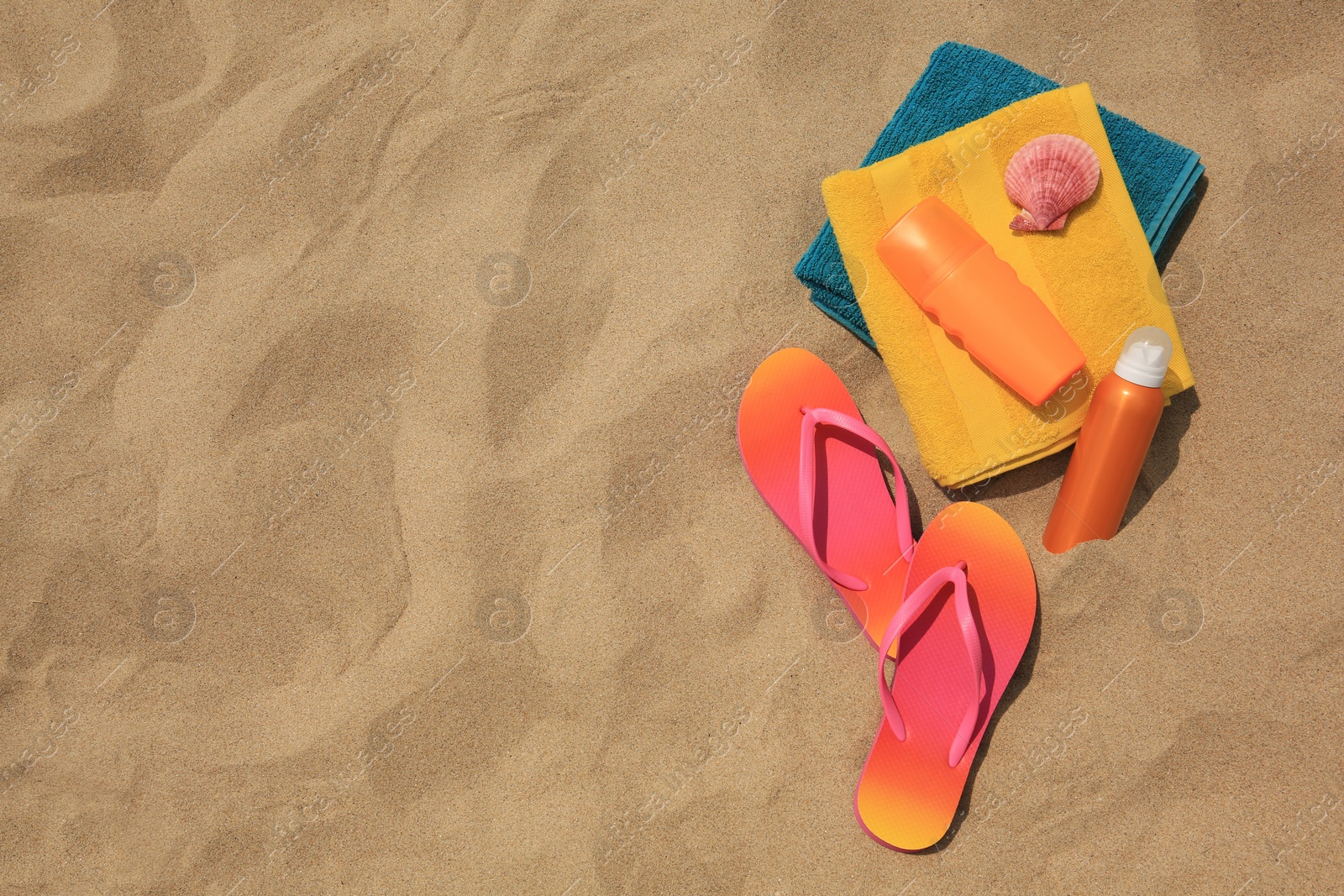 Photo of Flat lay composition with sunscreens on sand, space for text. Sun protection care