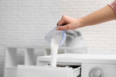 Woman pouring powder into drawer of washing machine indoors, closeup. Laundry day