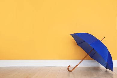 Photo of Beautiful open umbrella on floor near color wall with space for design