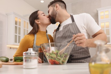 Lovely couple kissing while cooking in kitchen, low angle view