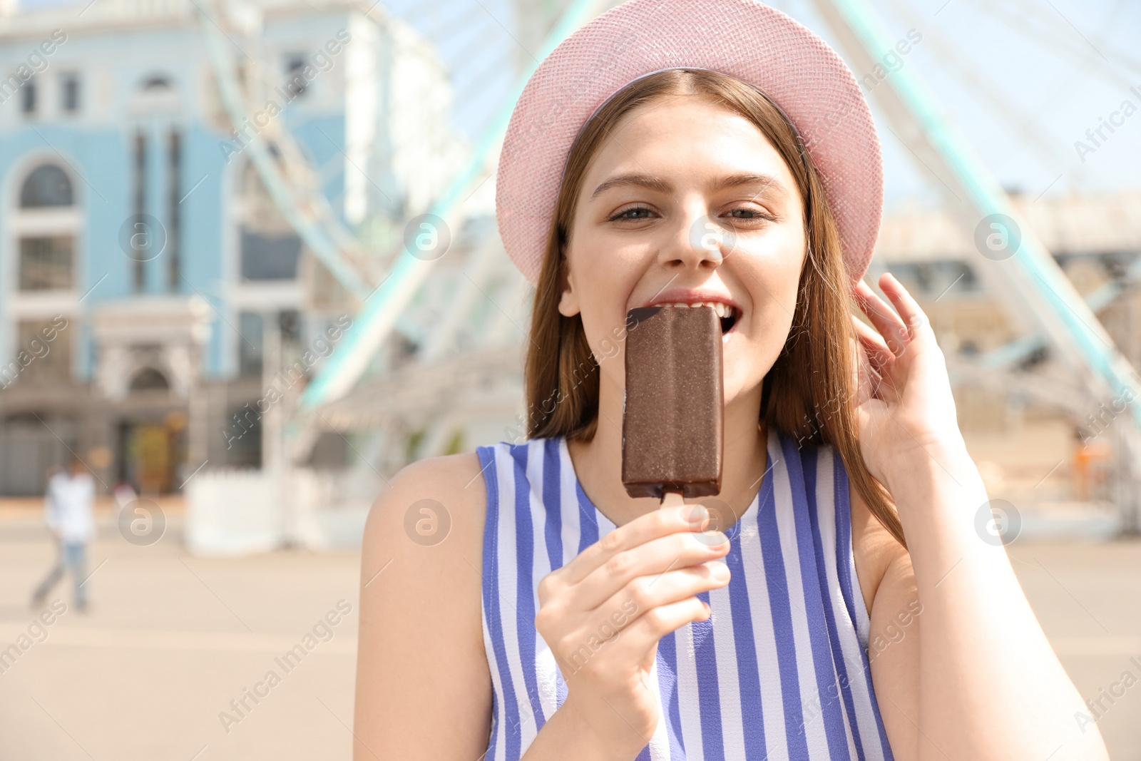 Photo of Young happy woman eating ice cream in amusement park. Space for text