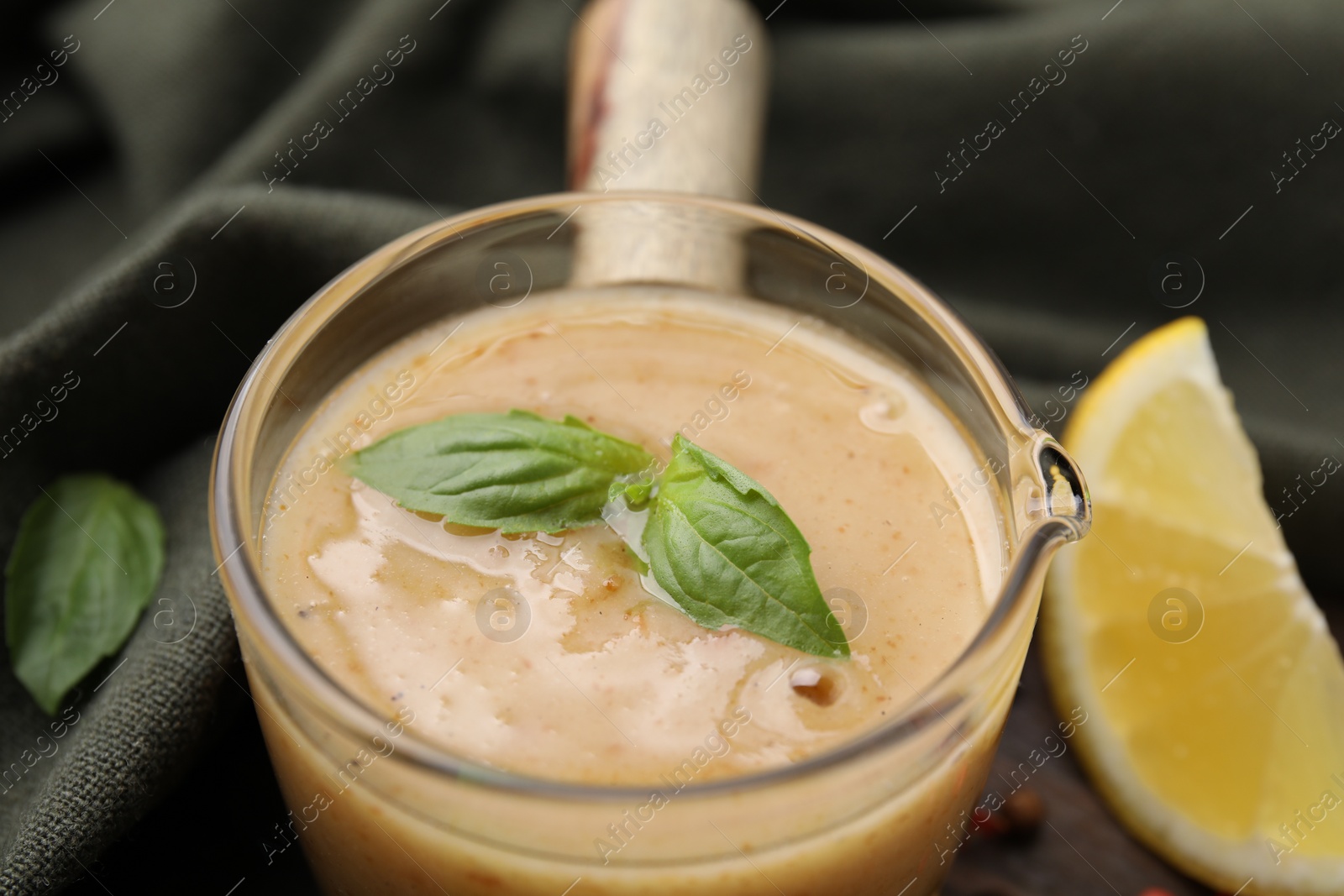 Photo of Delicious turkey gravy and basil on table, closeup