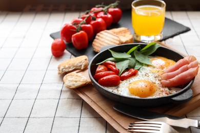 Photo of Delicious fried eggs with spinach, tomatoes and ham served on table. Space for text