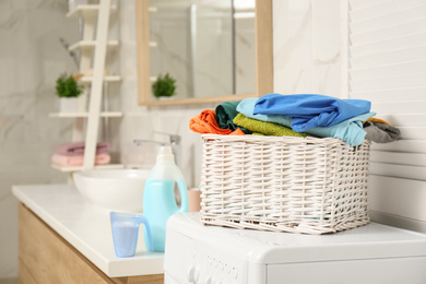 Wicker basket with laundry on washing machine in bathroom