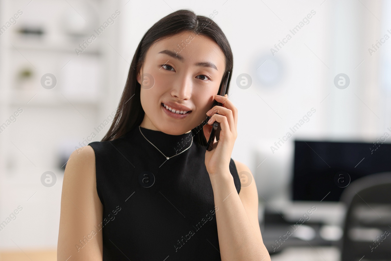 Photo of Portrait of smiling businesswoman talking on smartphone in office