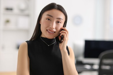 Photo of Portrait of smiling businesswoman talking on smartphone in office