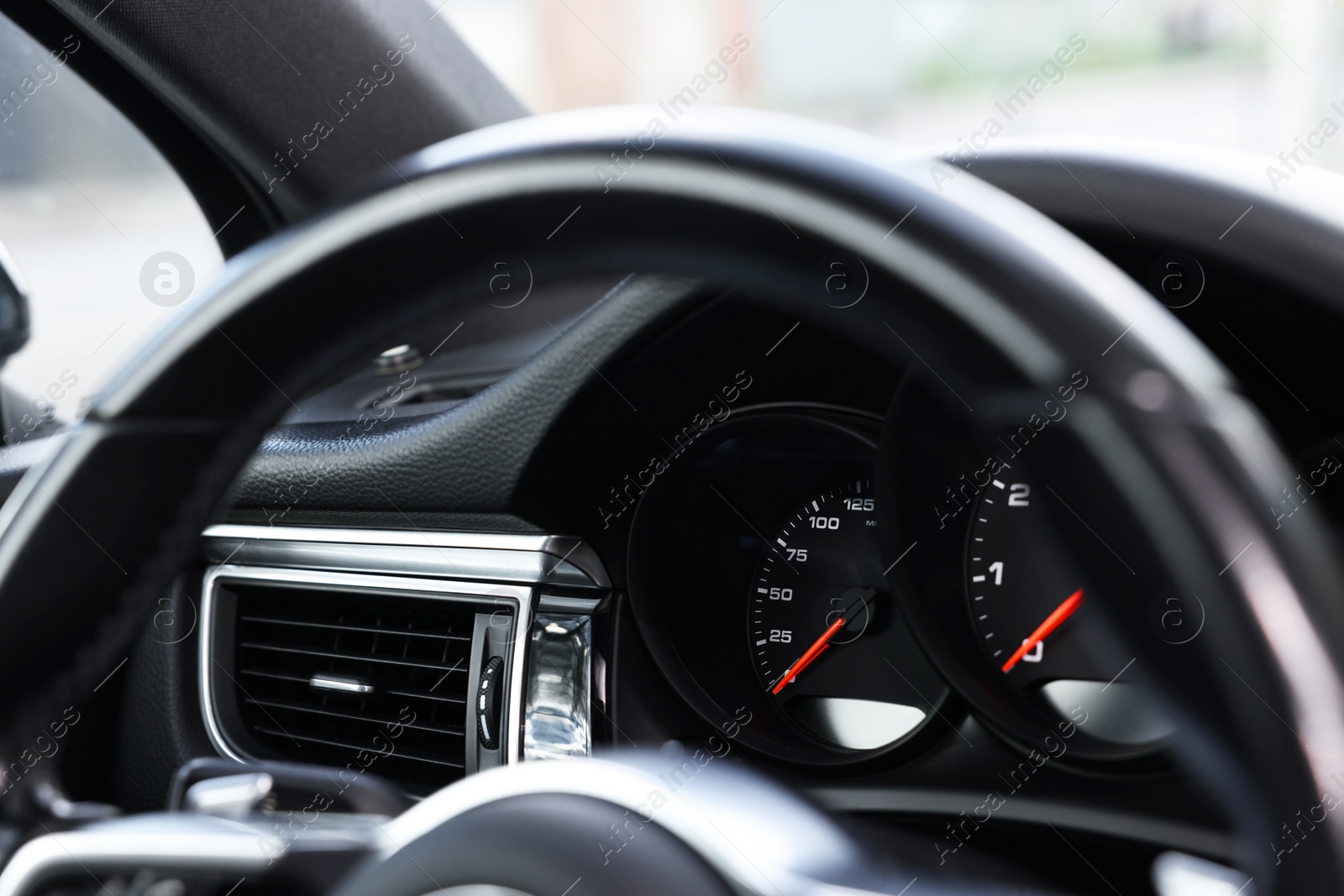 Photo of Steering wheel and speedometer inside modern black car, closeup view