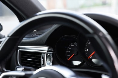 Steering wheel and speedometer inside modern black car, closeup view