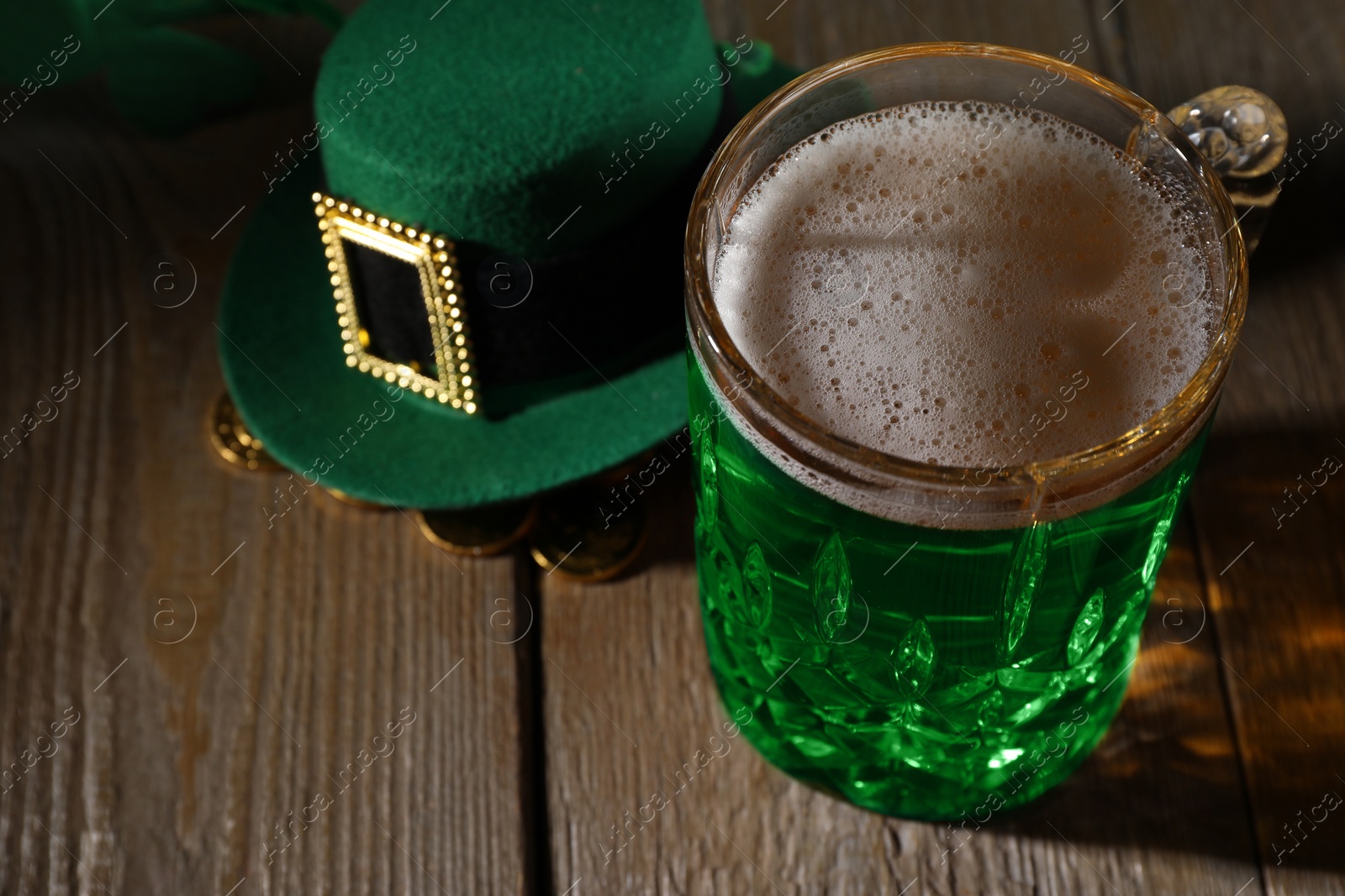 Photo of St. Patrick's day party. Green beer, leprechaun hat and gold on wooden table, closeup. Space for text