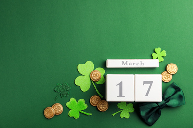 Flat lay composition with wooden block calendar on green background, space for text. St. Patrick's Day celebration