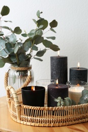 Photo of Tray with burning candles and green branches on table at white wall, space for text