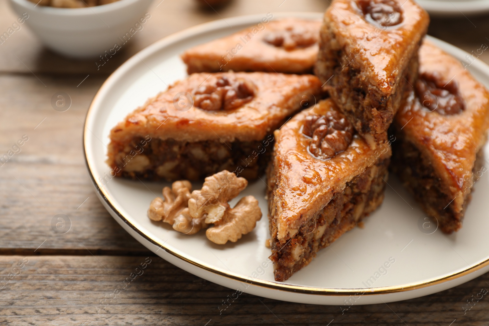 Photo of Delicious honey baklava with walnuts on wooden table, closeup