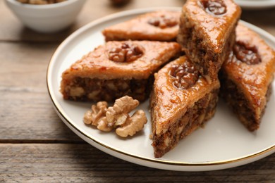 Photo of Delicious honey baklava with walnuts on wooden table, closeup