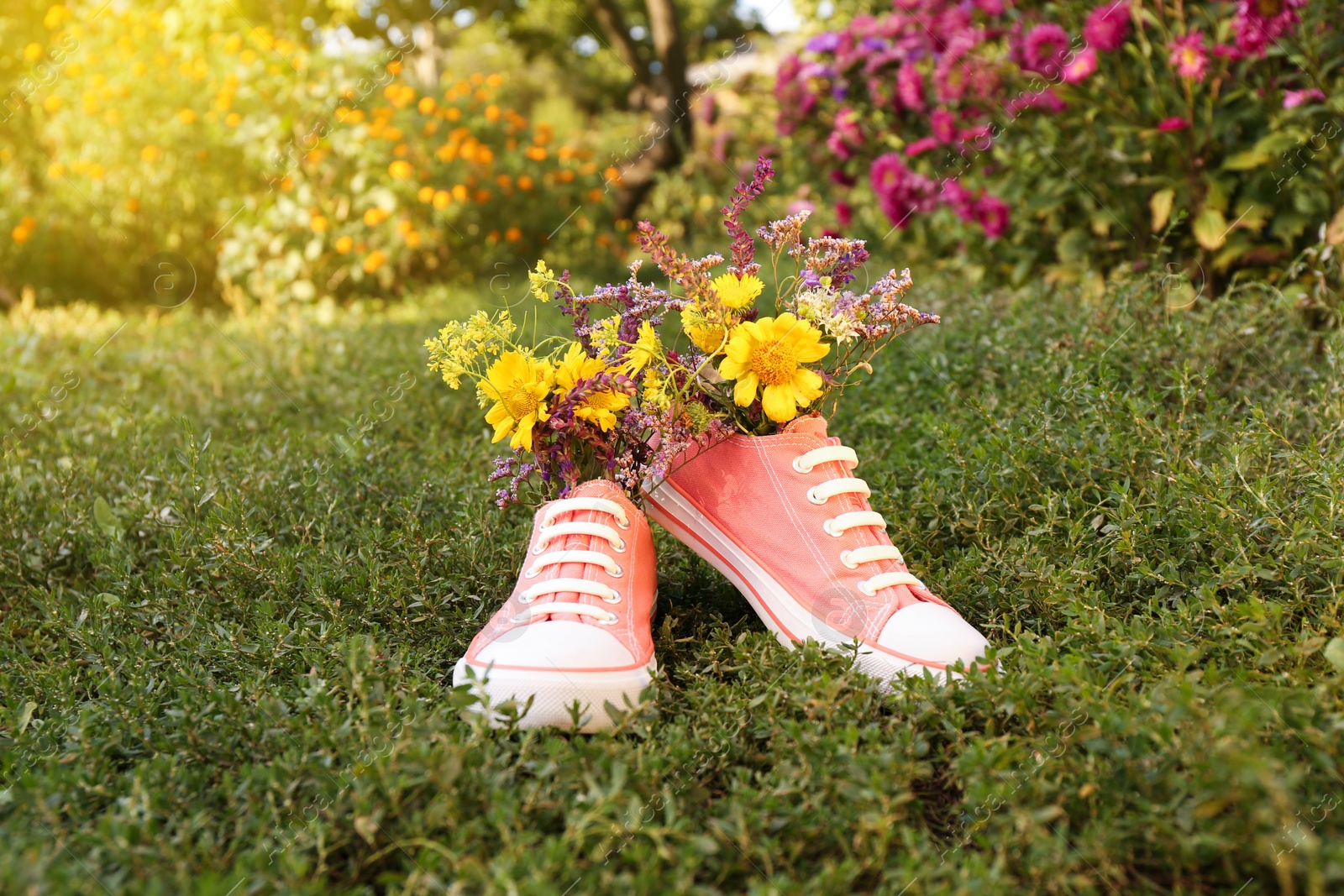 Photo of Shoes with beautiful flowers on grass outdoors