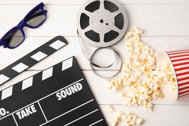 Photo of Flat lay composition with clapper, popcorn and 3D glasses on wooden background. Cinema snack