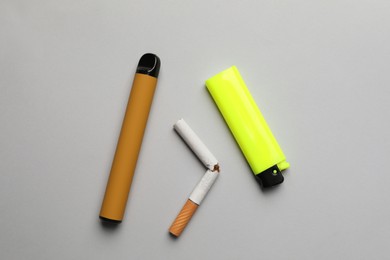 Lighter, electronic and regular cigarettes on light grey background, flat lay