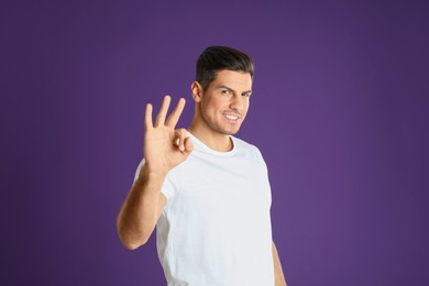 Man showing number three with his hand on purple background