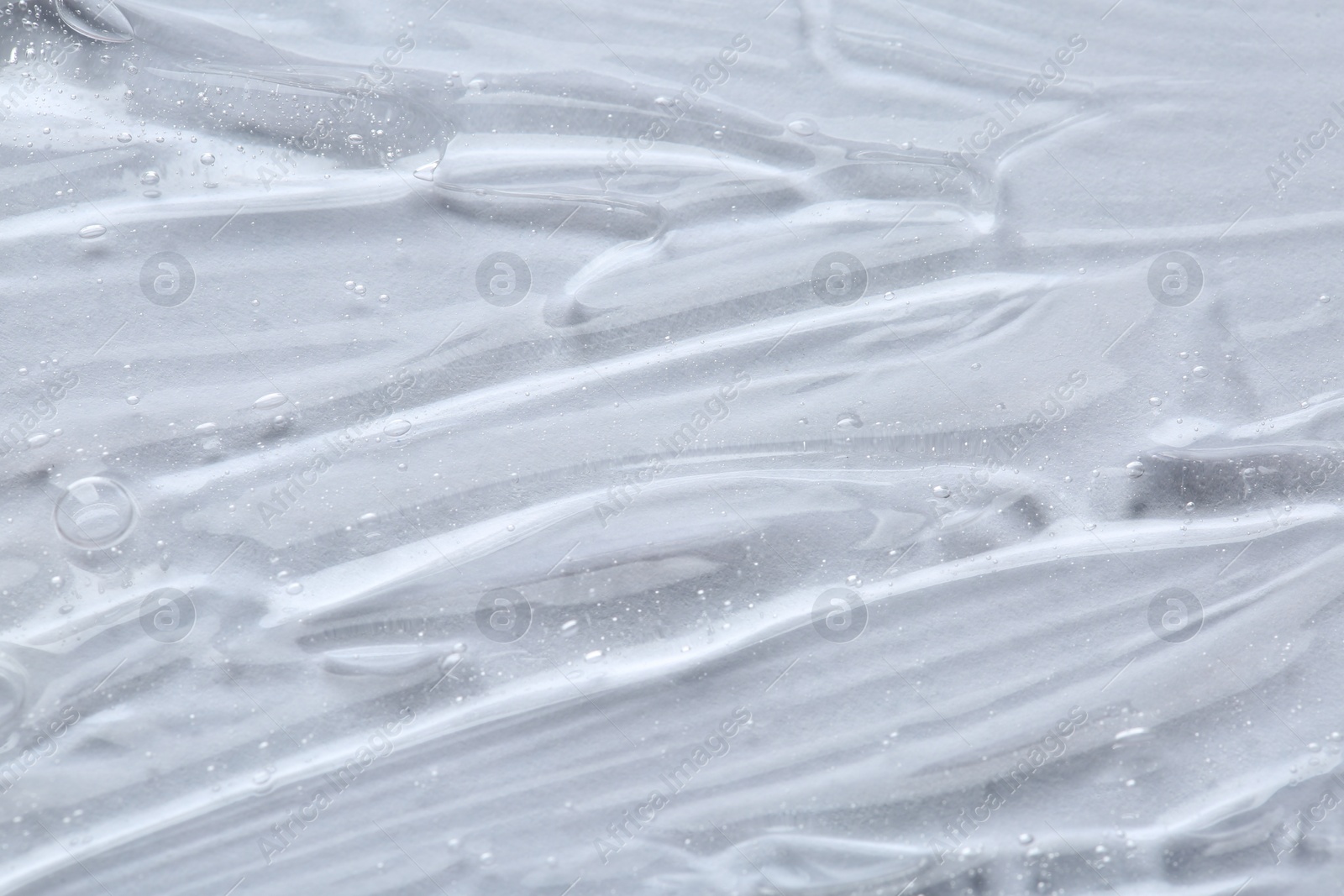 Photo of Clear cosmetic serum on white background, macro view