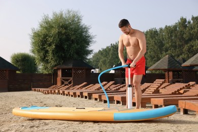 Photo of Man pumping up SUP board on river shore