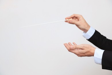 Photo of Professional conductor with baton on light grey background, closeup. Space for text