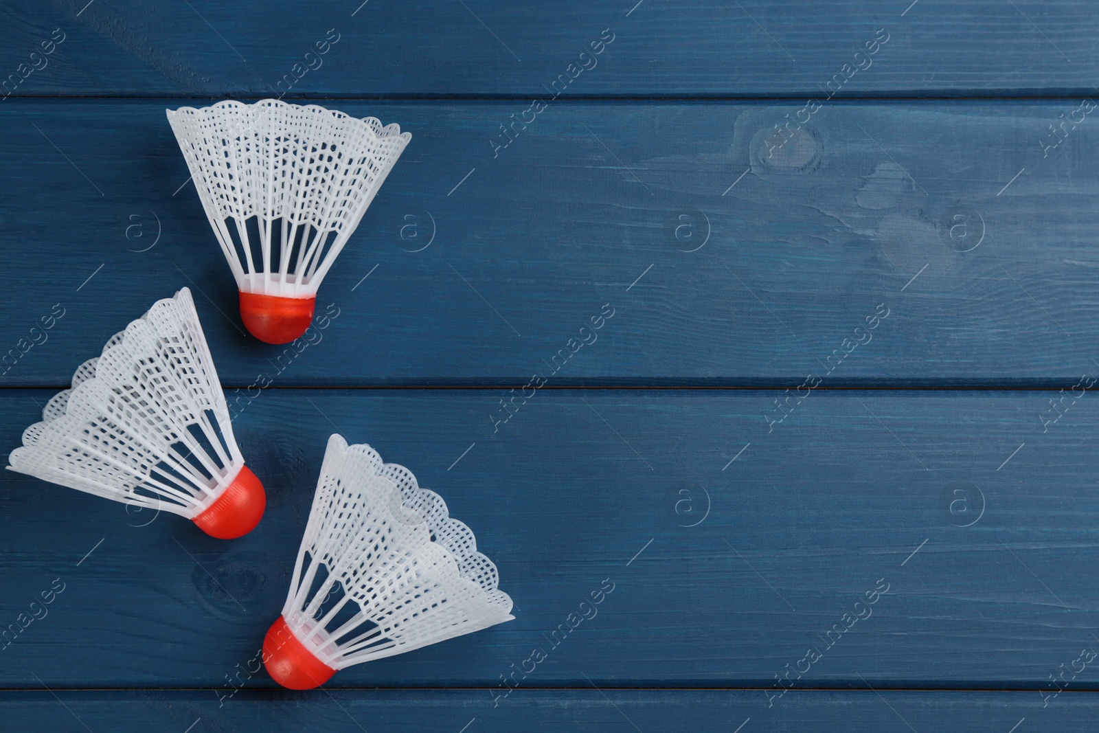 Photo of Shuttlecocks on blue wooden table, flat lay with space for text. Badminton equipment