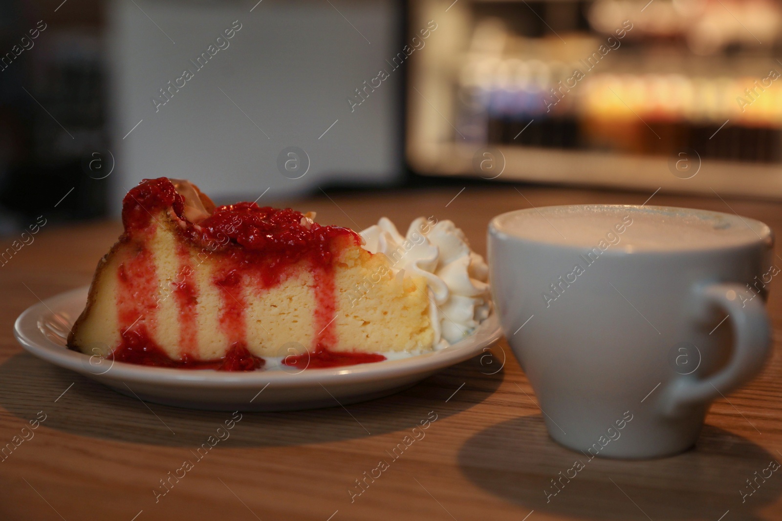 Photo of Cup of aromatic coffee and delicious dessert on wooden table in cafe, closeup