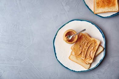 Flat lay composition with peanut butter and toasts on grey background