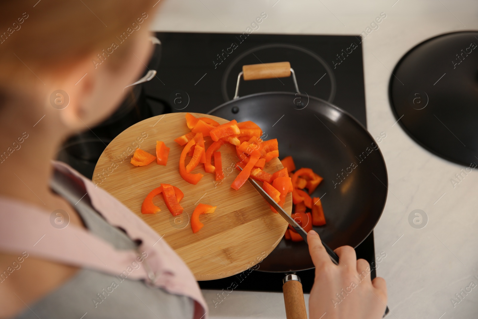 Photo of Young woman cooking on stove in kitchen, closeup