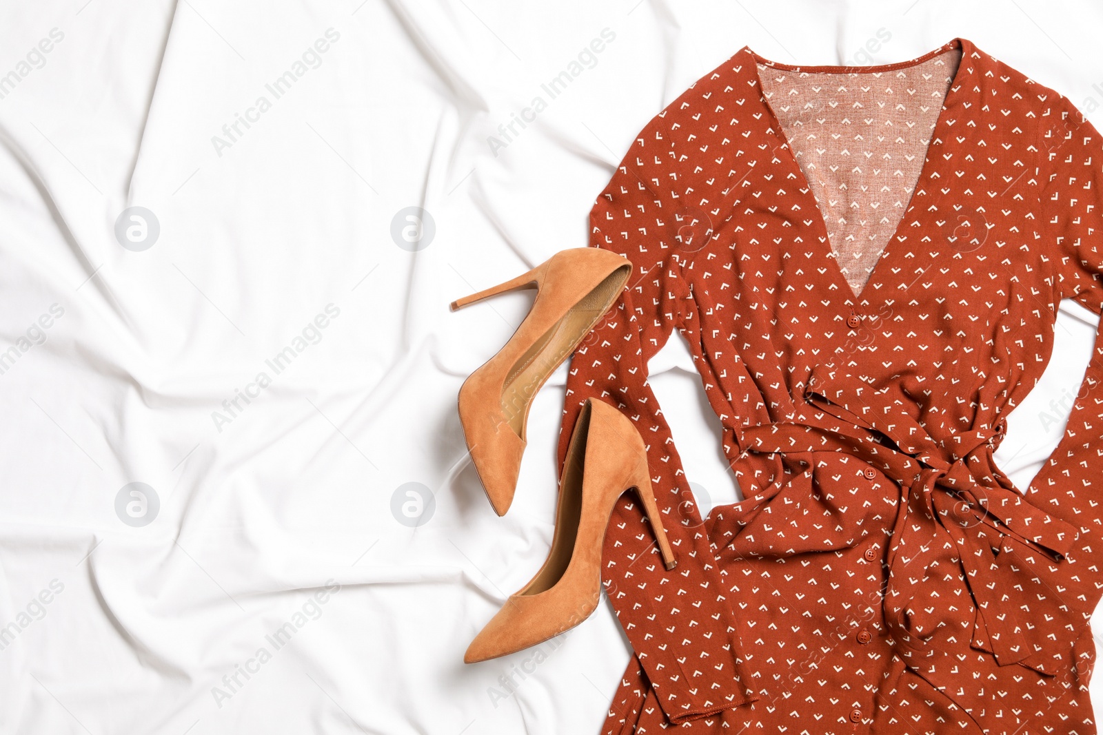 Photo of Stylish red dress and shoes on white fabric, flat lay. Space for text