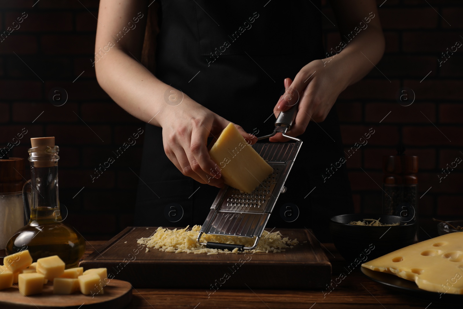 Photo of Woman grating cheese at wooden table, closeup