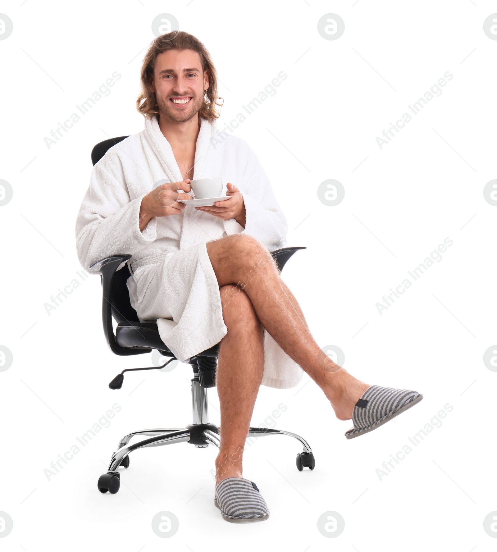 Photo of Young man in bathrobe with cup of drink on white background