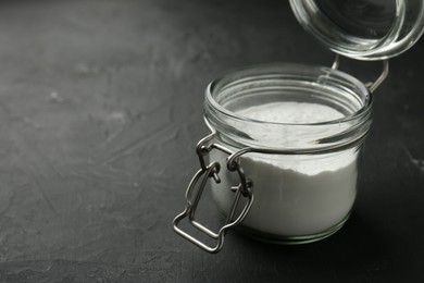 Photo of Baking powder in jar on black textured table, space for text