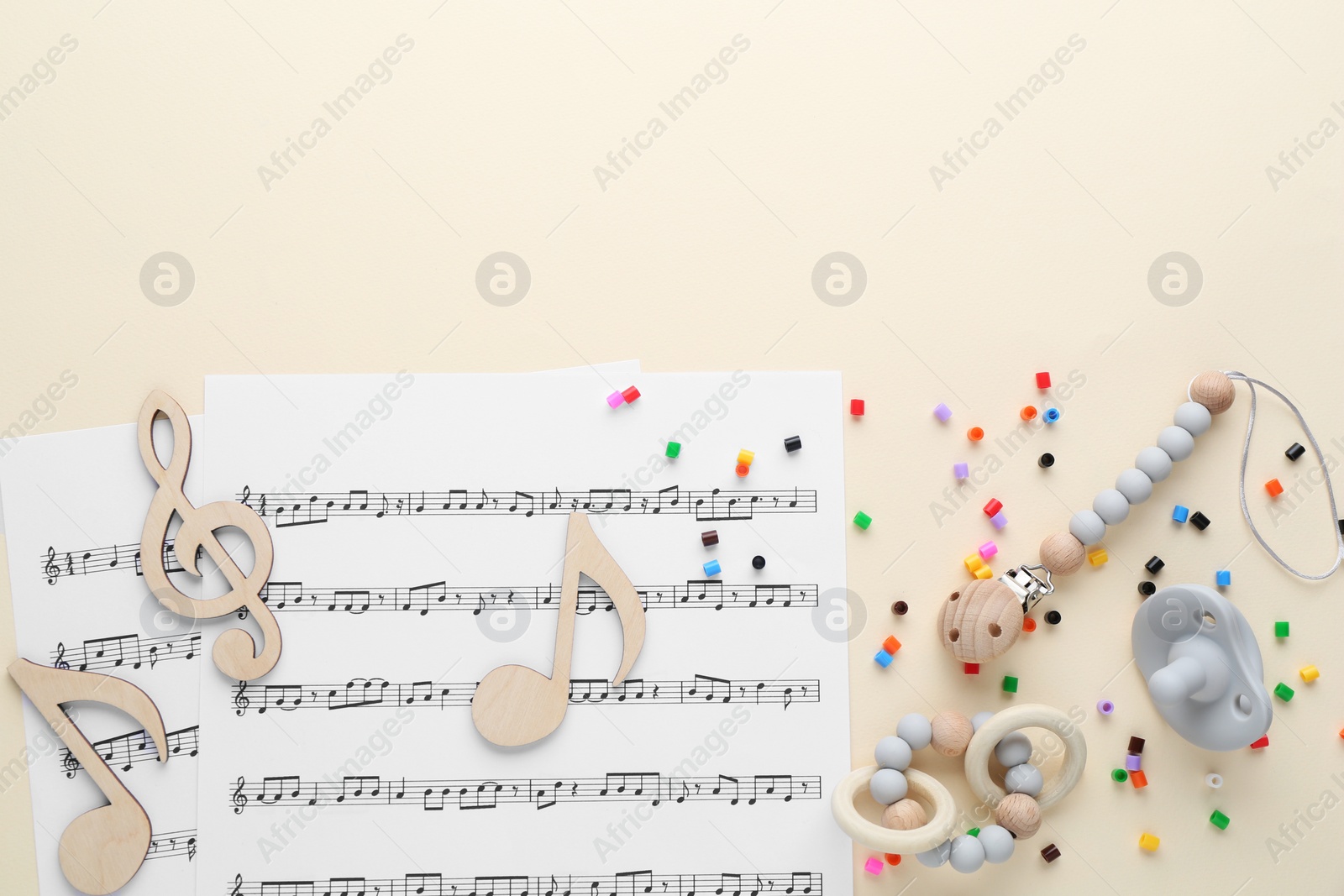 Photo of Wooden notes, music sheets and toys on beige background, flat lay with space for text. Baby song concept