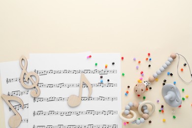 Wooden notes, music sheets and toys on beige background, flat lay with space for text. Baby song concept