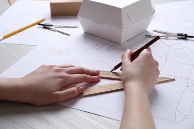 Photo of Woman creating packaging design at light wooden table, closeup