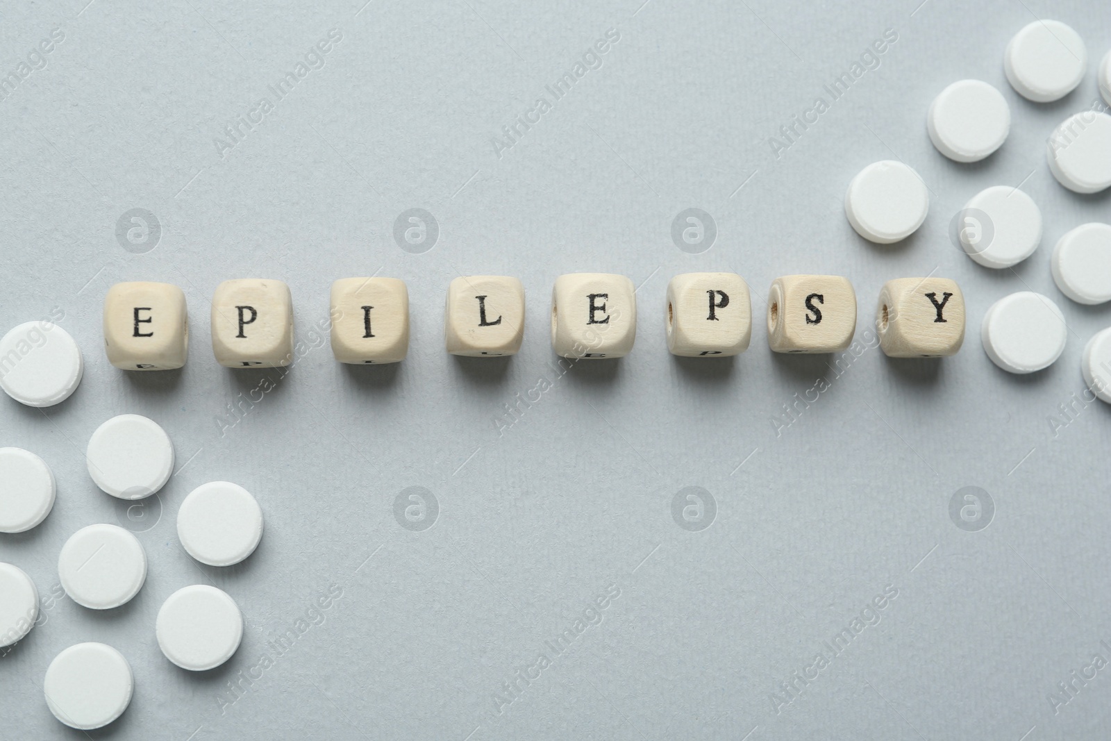 Photo of Word Epilepsy and pills on light grey background, flat lay