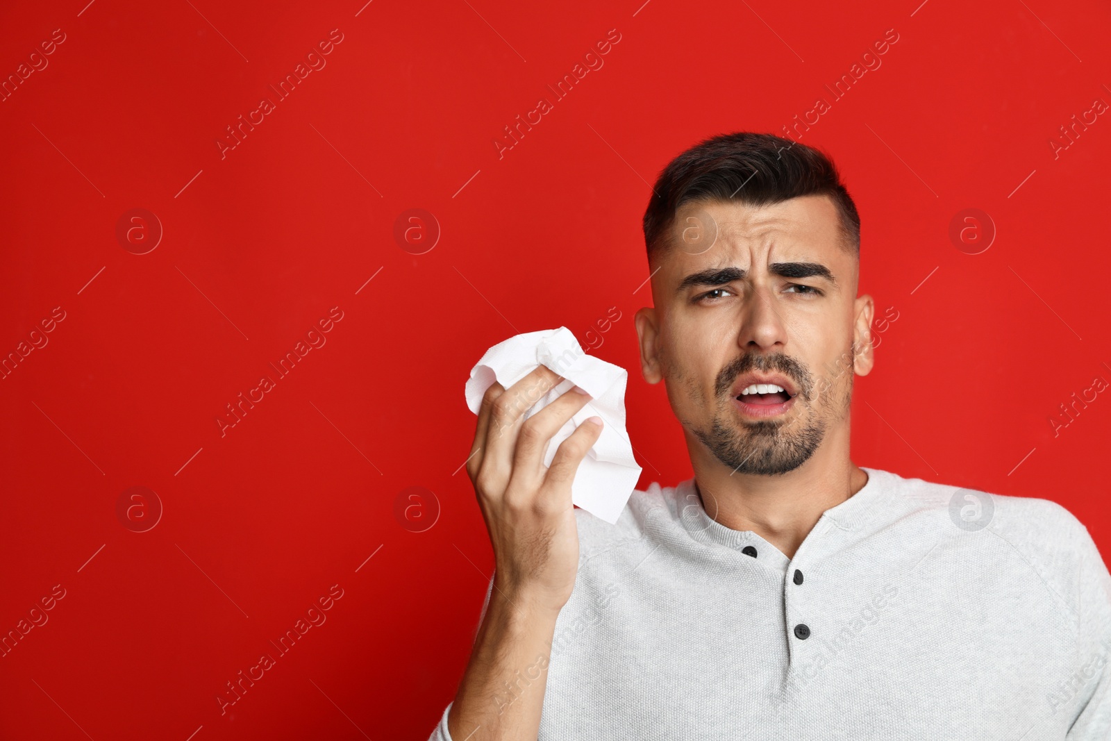 Image of Man sneezing on red background, space for text. Cold symptoms