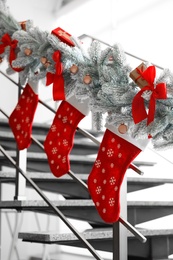 Photo of Santa stockings and garland on railing indoors. Christmas decor idea