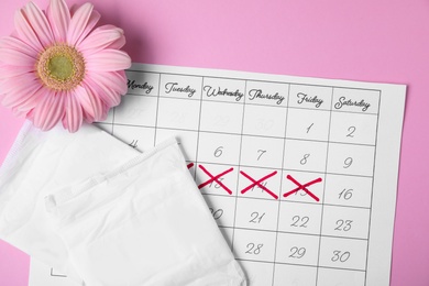 Photo of Flat lay composition with calendar, menstrual pads and gerbera flower on color background. Gynecological care