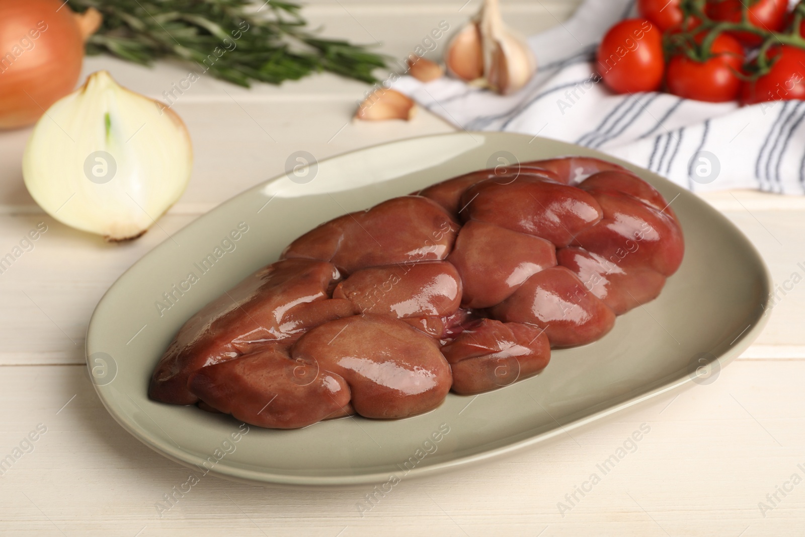 Photo of Fresh raw kidney meat and vegetables on white wooden table