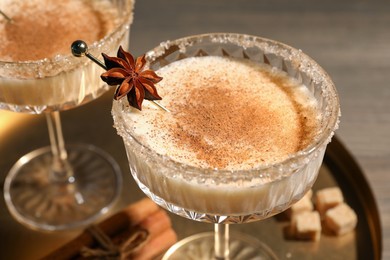 Photo of Delicious eggnog with cinnamon and anise on wooden table, closeup