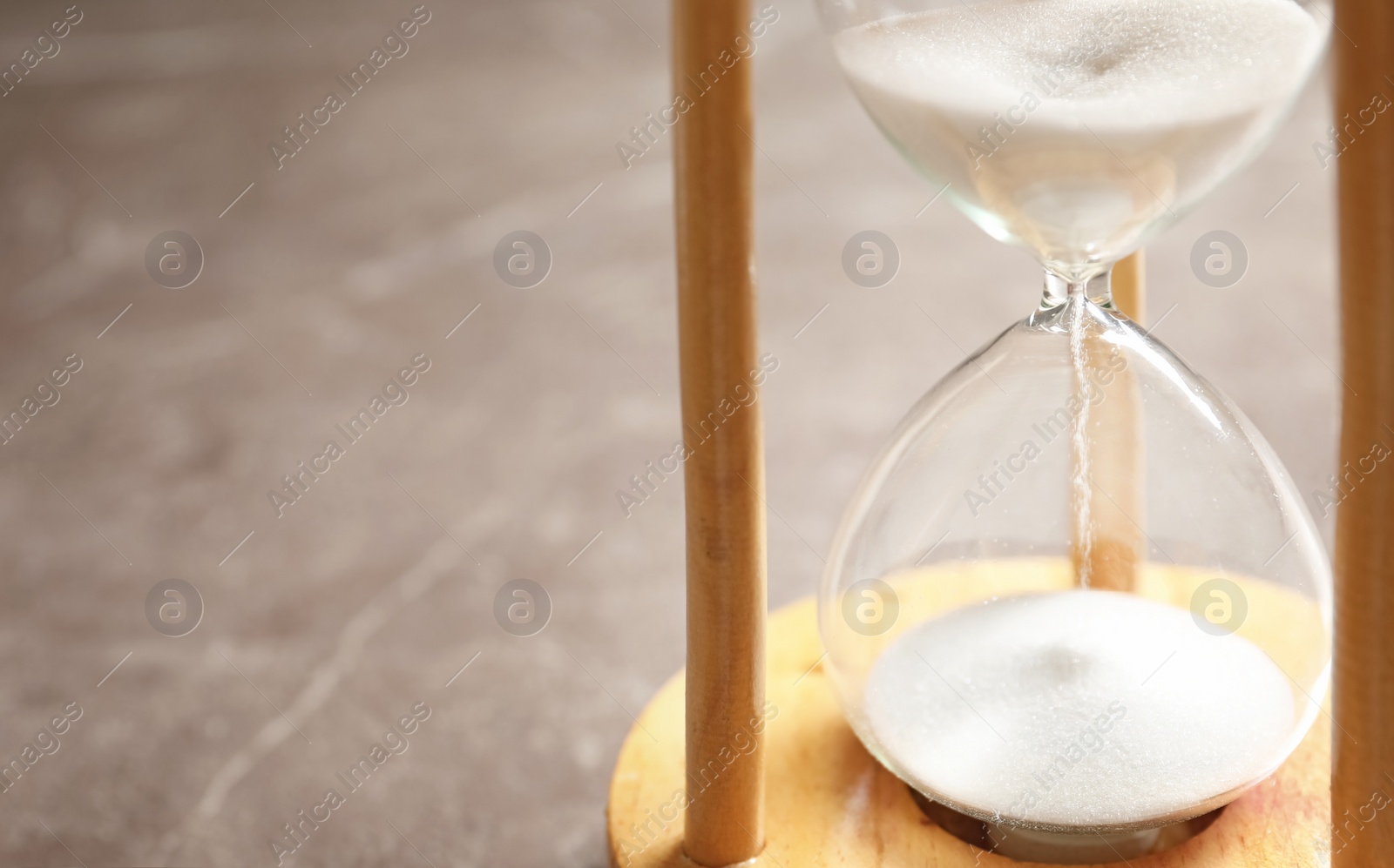 Photo of Hourglass with flowing sand on table. Time management