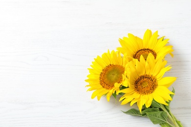 Photo of Yellow sunflowers on wooden background, top view