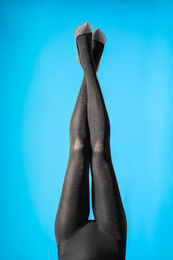 Photo of Woman wearing black tights and stylish shoes on blue background, closeup of legs