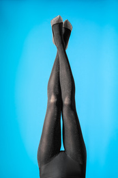 Woman wearing black tights and stylish shoes on blue background, closeup of legs