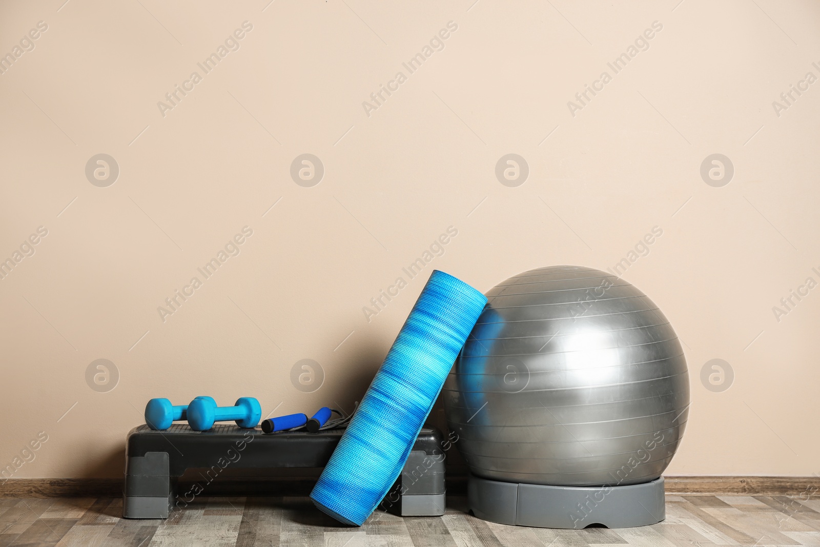 Photo of Set of fitness inventory on floor near color wall. Space for text