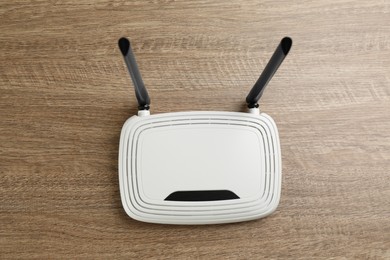 Photo of Modern Wi-Fi router on wooden background, top view